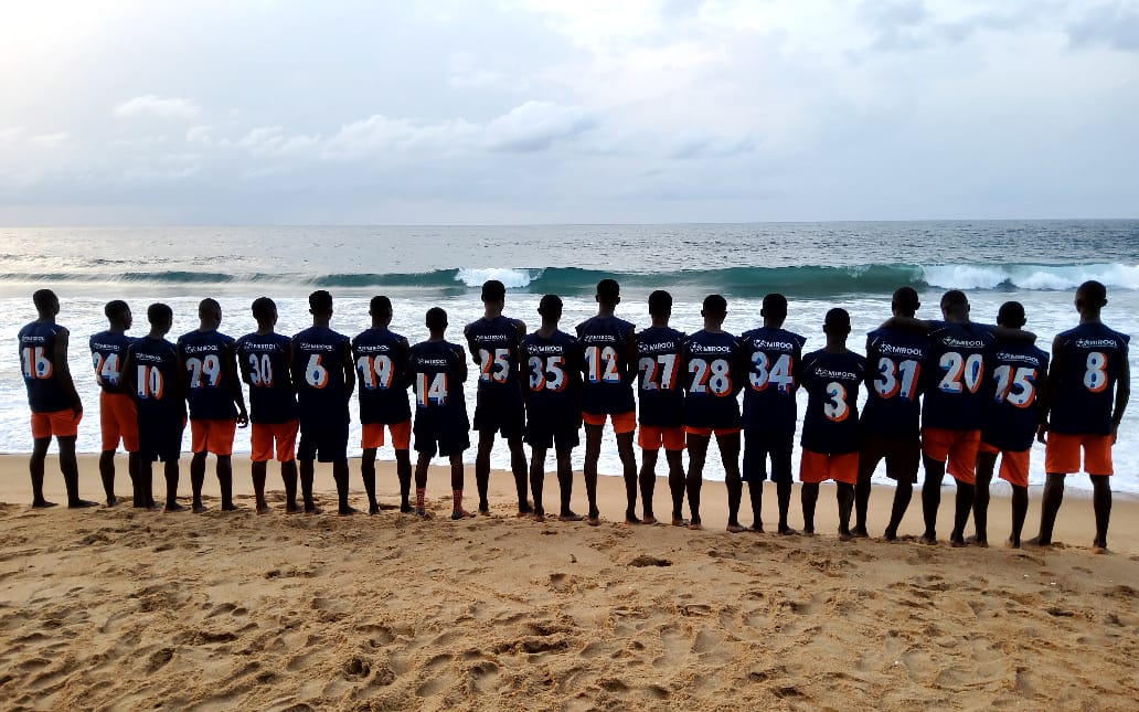L'équipe alignée face à l'océan, de dos, en maillots numérotés