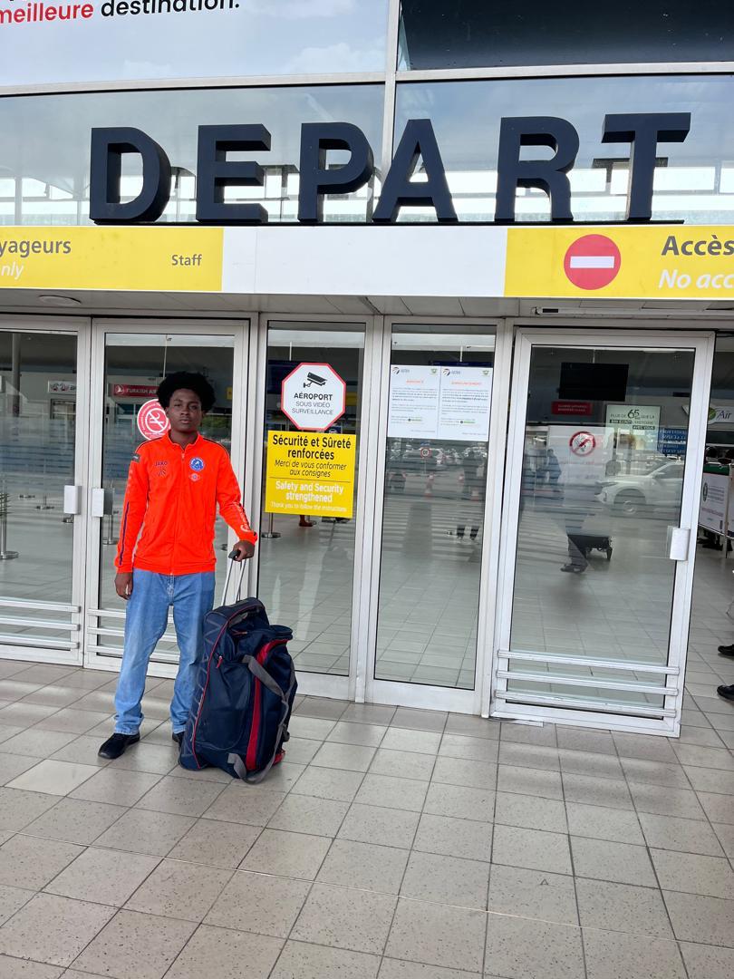Joueur de JR MIROOL CI avec ses bagages devant la zone Départ de l'aéroport