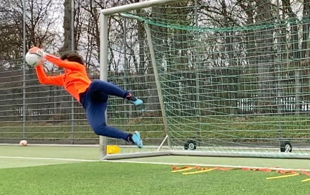 Gardien de but plongeant et captant le ballon devant sa cage