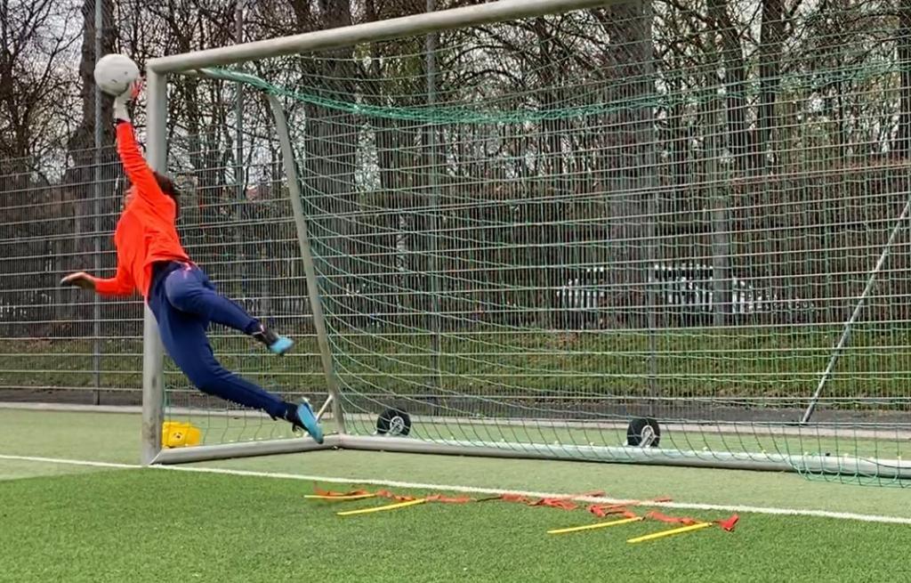 Gardien de but s'envolant pour détourner le ballon en lucarne