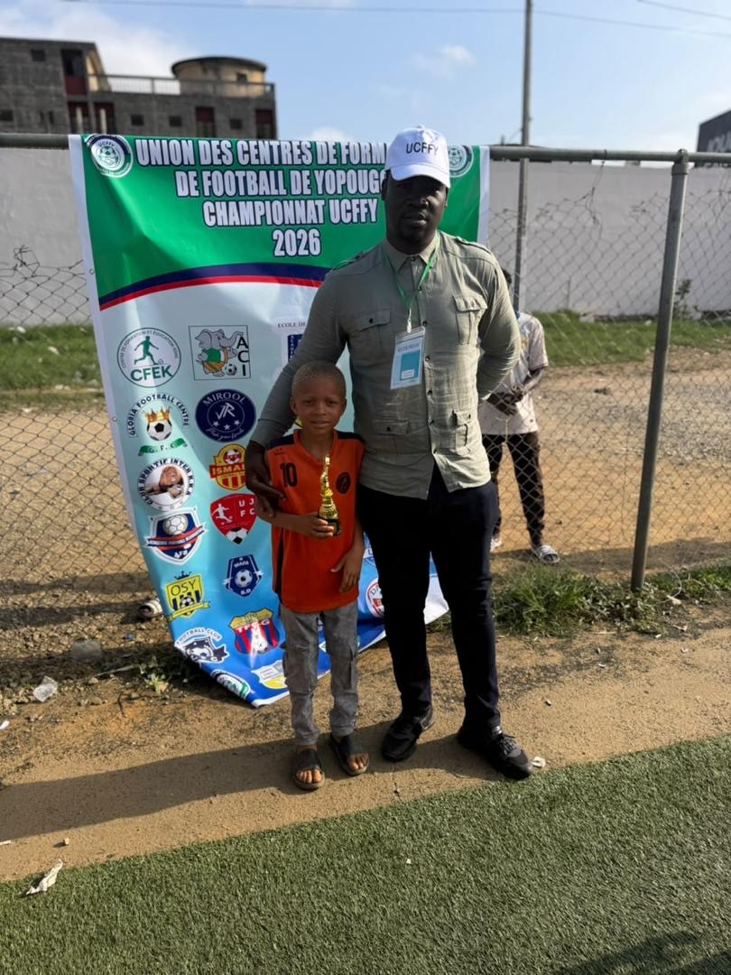 Un jeune joueur de JR MIROOL CI recevant un trophée d'un responsable du tournoi