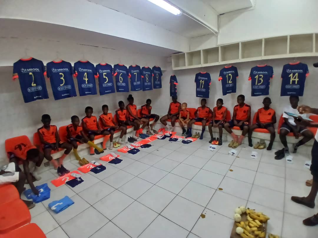 Les joueurs assis dans le vestiaire avant le match, maillots accrochés